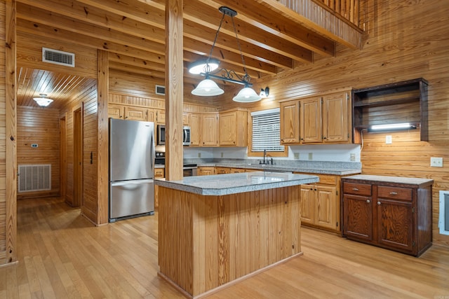 kitchen featuring visible vents, appliances with stainless steel finishes, light wood-type flooring, and wooden walls