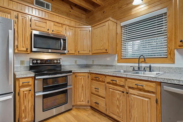 kitchen featuring visible vents, tile countertops, light wood-type flooring, stainless steel appliances, and a sink