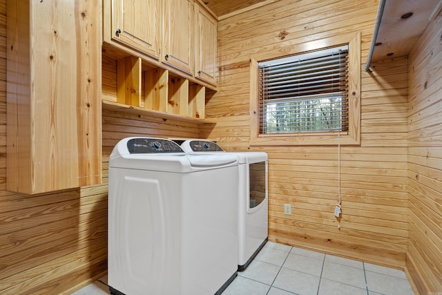 washroom with light tile patterned flooring, cabinet space, independent washer and dryer, and wood walls