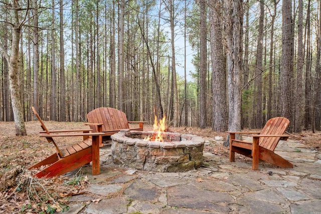 view of patio / terrace with a fire pit and a view of trees