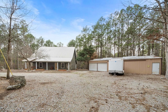 exterior space with a garage, covered porch, metal roof, and an outdoor structure