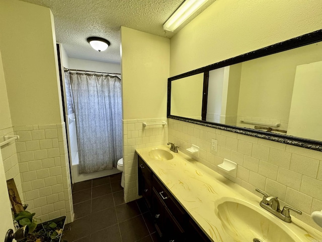 bathroom featuring tile patterned flooring, a textured ceiling, toilet, and a sink