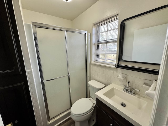 full bathroom featuring toilet, a stall shower, tile walls, and vanity