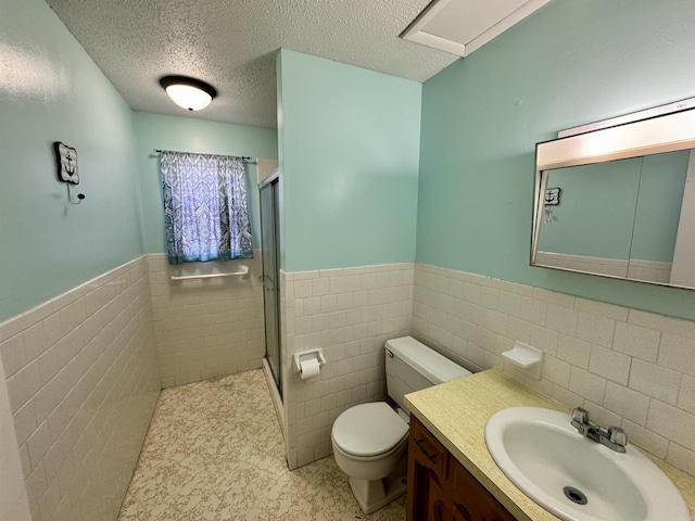 full bathroom with a shower stall, toilet, wainscoting, and a textured ceiling