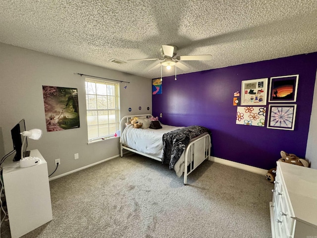 carpeted bedroom with a textured ceiling, baseboards, visible vents, and ceiling fan