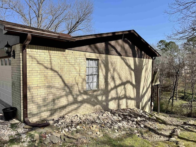 view of side of home featuring a garage and brick siding