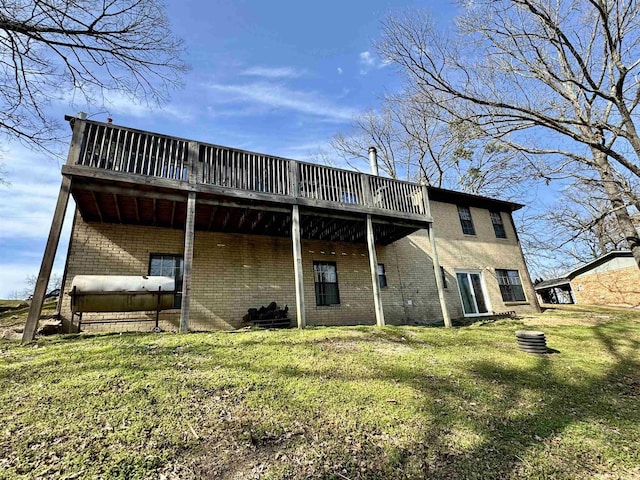 back of house featuring brick siding, a deck, heating fuel, and a yard