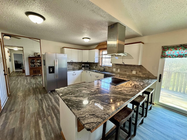 kitchen featuring a sink, a peninsula, dark wood finished floors, and stainless steel fridge with ice dispenser