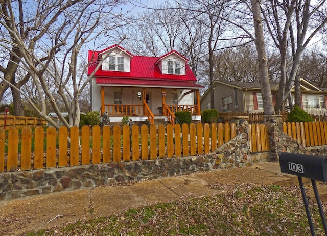 view of front of house with a porch, a fenced front yard, and metal roof