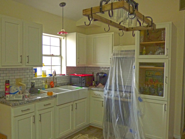 kitchen featuring decorative backsplash, pendant lighting, black microwave, and a sink