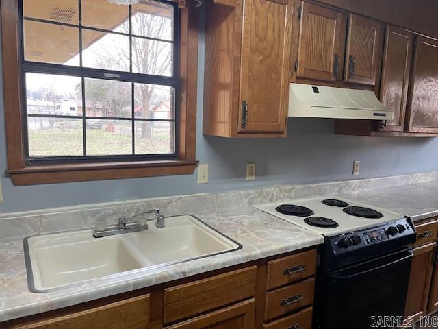 kitchen featuring under cabinet range hood, a sink, light countertops, and black electric range