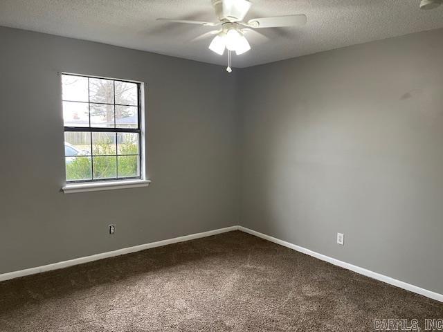 unfurnished room featuring ceiling fan, a textured ceiling, baseboards, and dark colored carpet