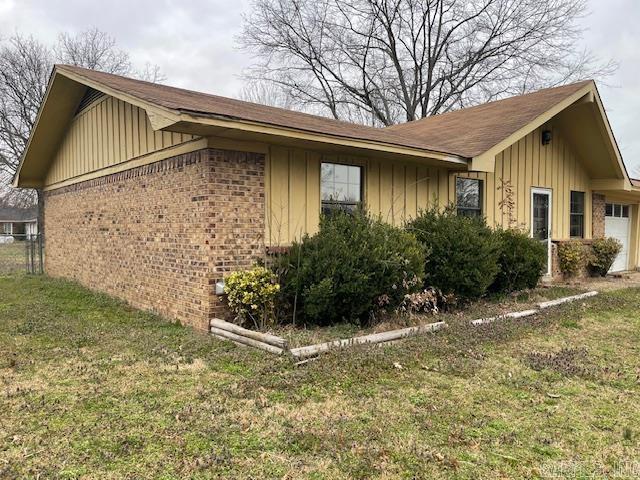 view of side of property with board and batten siding, a yard, and brick siding