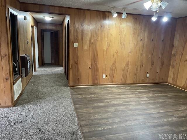 unfurnished room featuring wood finished floors, heating unit, a textured ceiling, and wood walls