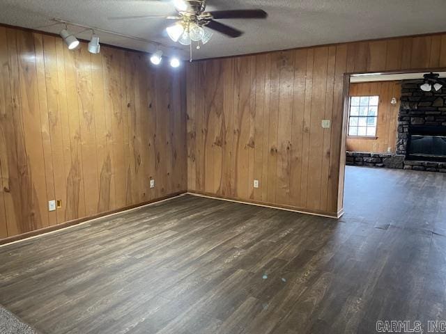 interior space with wood finished floors, a fireplace, ceiling fan, track lighting, and a textured ceiling