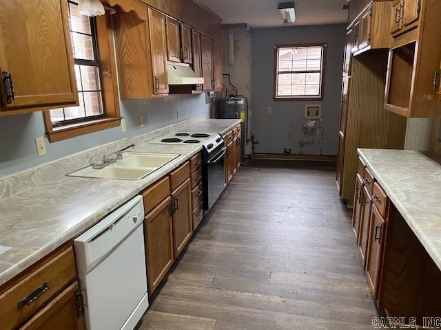 kitchen featuring a sink, under cabinet range hood, range with electric stovetop, brown cabinetry, and dishwasher