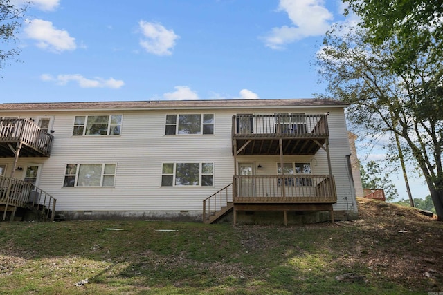 back of house featuring crawl space, stairway, and a lawn