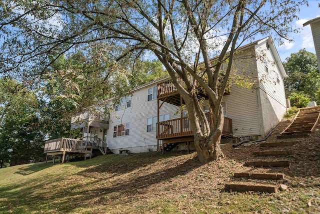 back of house with a wooden deck, a lawn, a balcony, and stairs