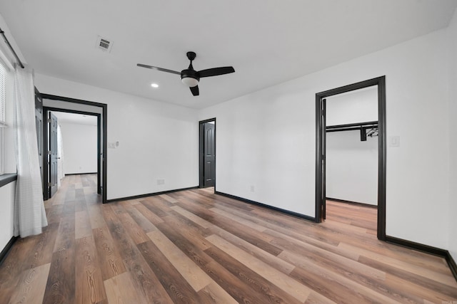 unfurnished bedroom with light wood-type flooring, visible vents, a walk in closet, recessed lighting, and baseboards