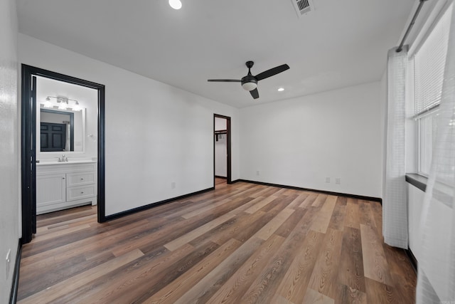 unfurnished bedroom with visible vents, baseboards, recessed lighting, wood finished floors, and a sink