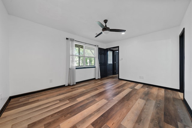 empty room with a ceiling fan, baseboards, and wood finished floors