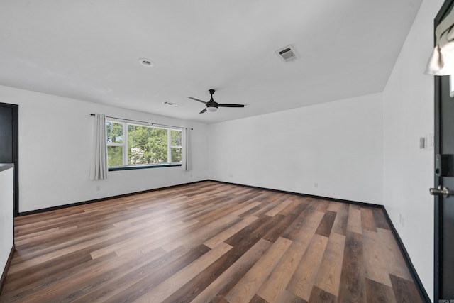 empty room featuring visible vents, baseboards, wood finished floors, and a ceiling fan