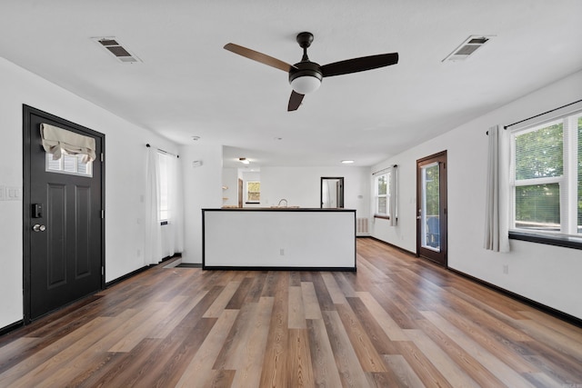 unfurnished living room with a wealth of natural light, visible vents, and wood finished floors