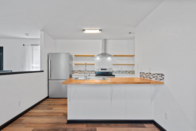 kitchen with a sink, wall chimney range hood, butcher block countertops, stainless steel appliances, and open shelves