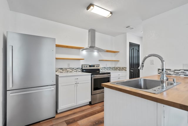 kitchen featuring a sink, stainless steel appliances, wall chimney exhaust hood, and open shelves