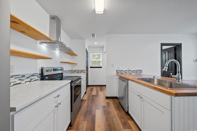 kitchen featuring dark wood-style floors, open shelves, island exhaust hood, a sink, and appliances with stainless steel finishes