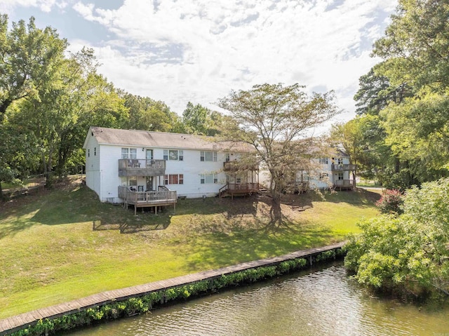 back of house featuring a lawn, a deck with water view, and a balcony