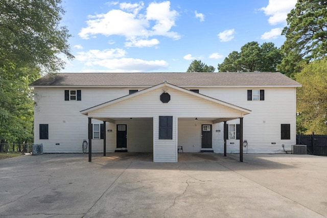 view of front of house with an attached carport, central AC unit, fence, and driveway