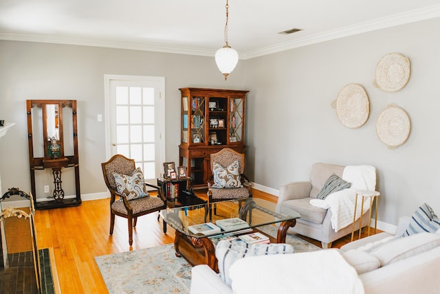 living room featuring light wood finished floors, crown molding, and baseboards