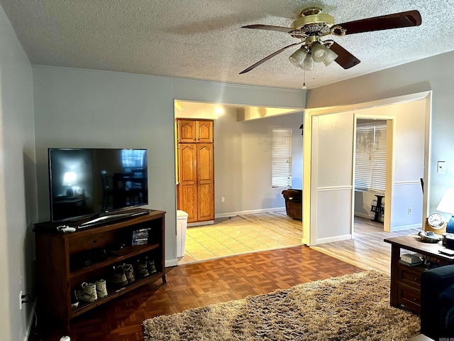 living area featuring baseboards, a textured ceiling, and a ceiling fan