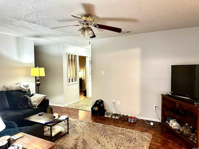 living room with visible vents, baseboards, a textured ceiling, and ceiling fan