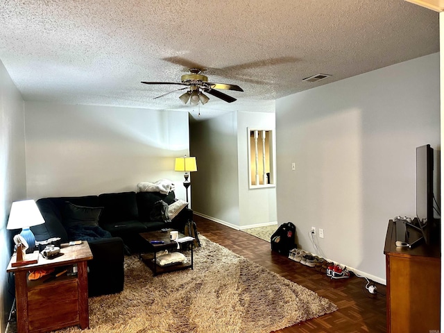 living room with baseboards, a ceiling fan, visible vents, and a textured ceiling