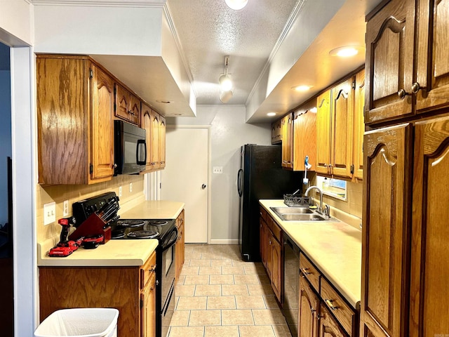 kitchen with black appliances, crown molding, light countertops, a textured ceiling, and a sink