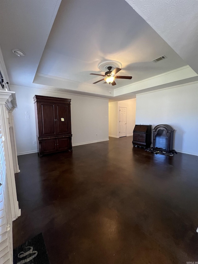 interior space with a ceiling fan, baseboards, visible vents, a tray ceiling, and finished concrete floors