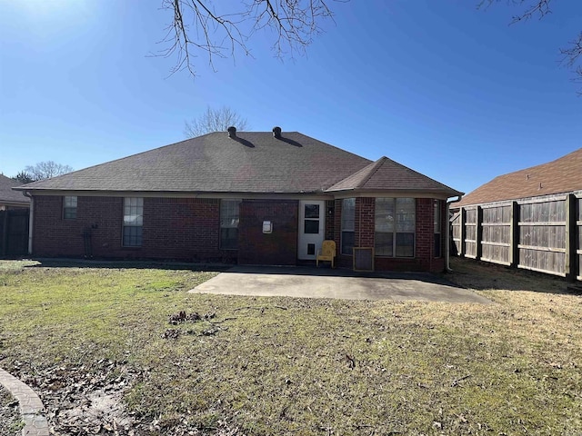 back of house featuring a patio, fence, roof with shingles, a yard, and brick siding