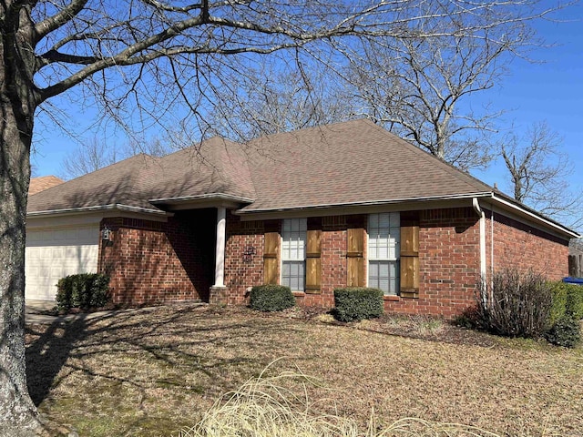 ranch-style home featuring brick siding, an attached garage, and a shingled roof