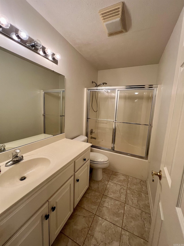 bathroom featuring visible vents, toilet, vanity, shower / bath combination with glass door, and a textured ceiling