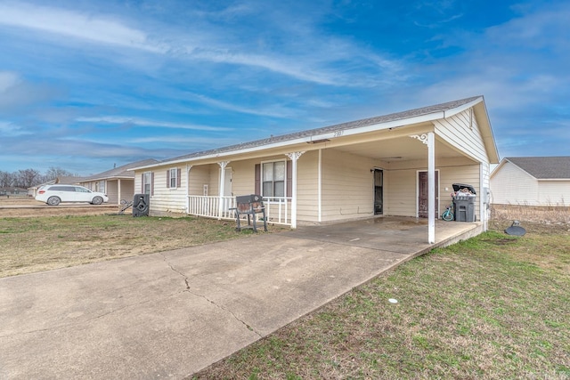 ranch-style home featuring a carport, covered porch, concrete driveway, and a front lawn