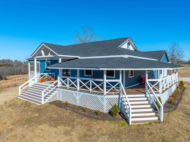 view of front of home with covered porch, a front yard, stairs, and roof with shingles