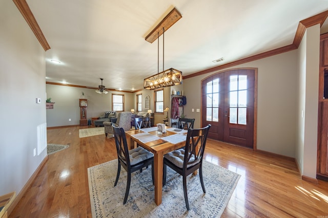 dining space with baseboards, visible vents, french doors, crown molding, and light wood-type flooring