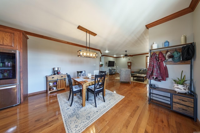 dining area featuring baseboards, light wood-style floors, crown molding, and ceiling fan with notable chandelier