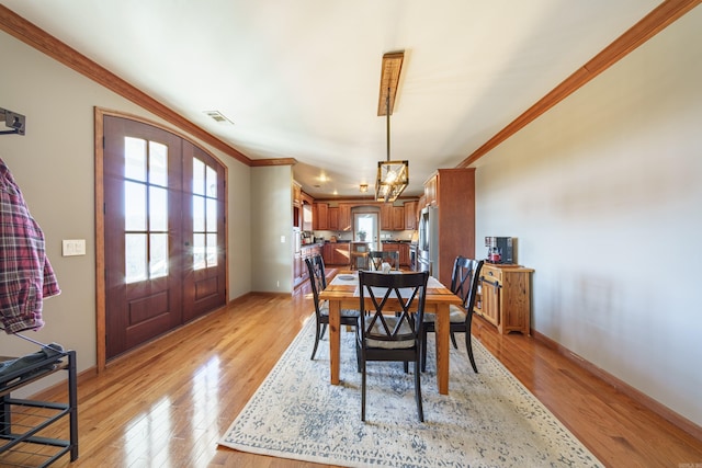 dining space with light wood-type flooring, visible vents, french doors, crown molding, and baseboards