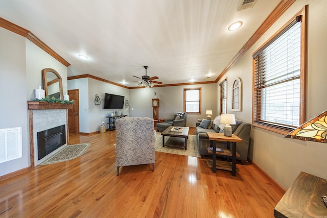 living area featuring visible vents, a fireplace with flush hearth, light wood-style floors, and ceiling fan