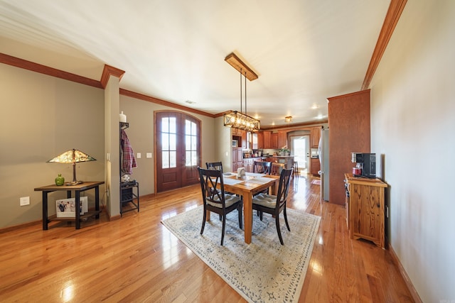 dining room featuring french doors, light wood-type flooring, and ornamental molding