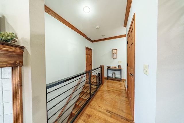 corridor featuring crown molding, light wood-style flooring, and an upstairs landing