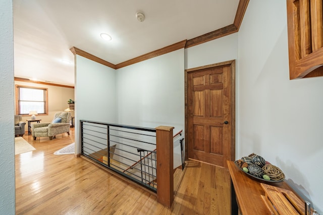 corridor featuring an upstairs landing, crown molding, and wood finished floors